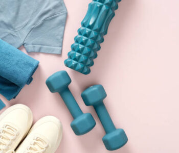 Female fitness flat lay, sneakers, dumbbells, on pastel pink background.Feminine sports, workouts, healthy lifestyle.